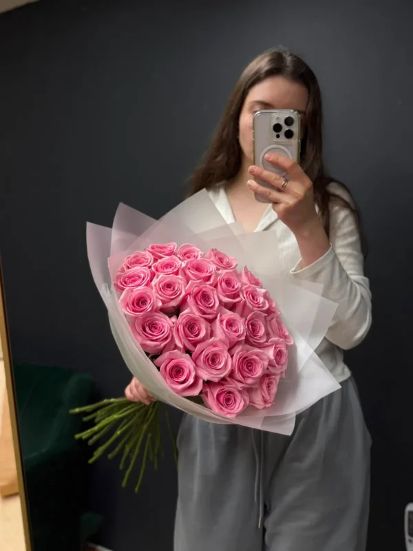Woman holding a large Ecuadorian pink rose bouquet in translucent wrap