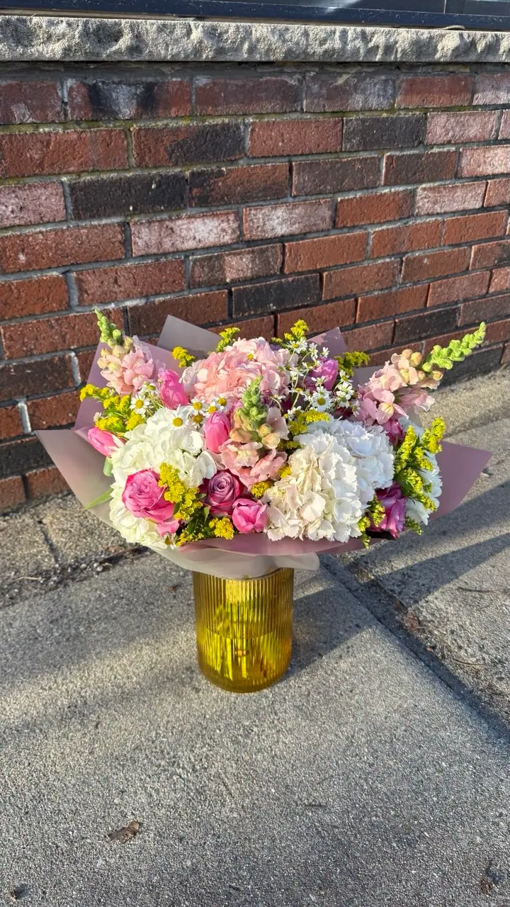 Colorful floral arrangement in a yellow vase by Wildflower Boston